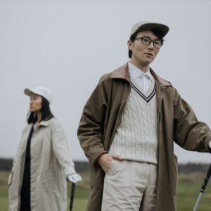 Home Two fashionable Asian golfers with clubs on a golf course, showcasing style and lifestyle.